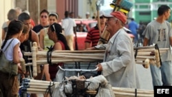 Un hombre vende escobas y utensilios de limpieza. 