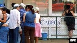 Varias personas hacen cola frente a una Casa de Cambio (CADECA).